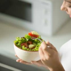 Bowl of fresh green salad hold in female hands