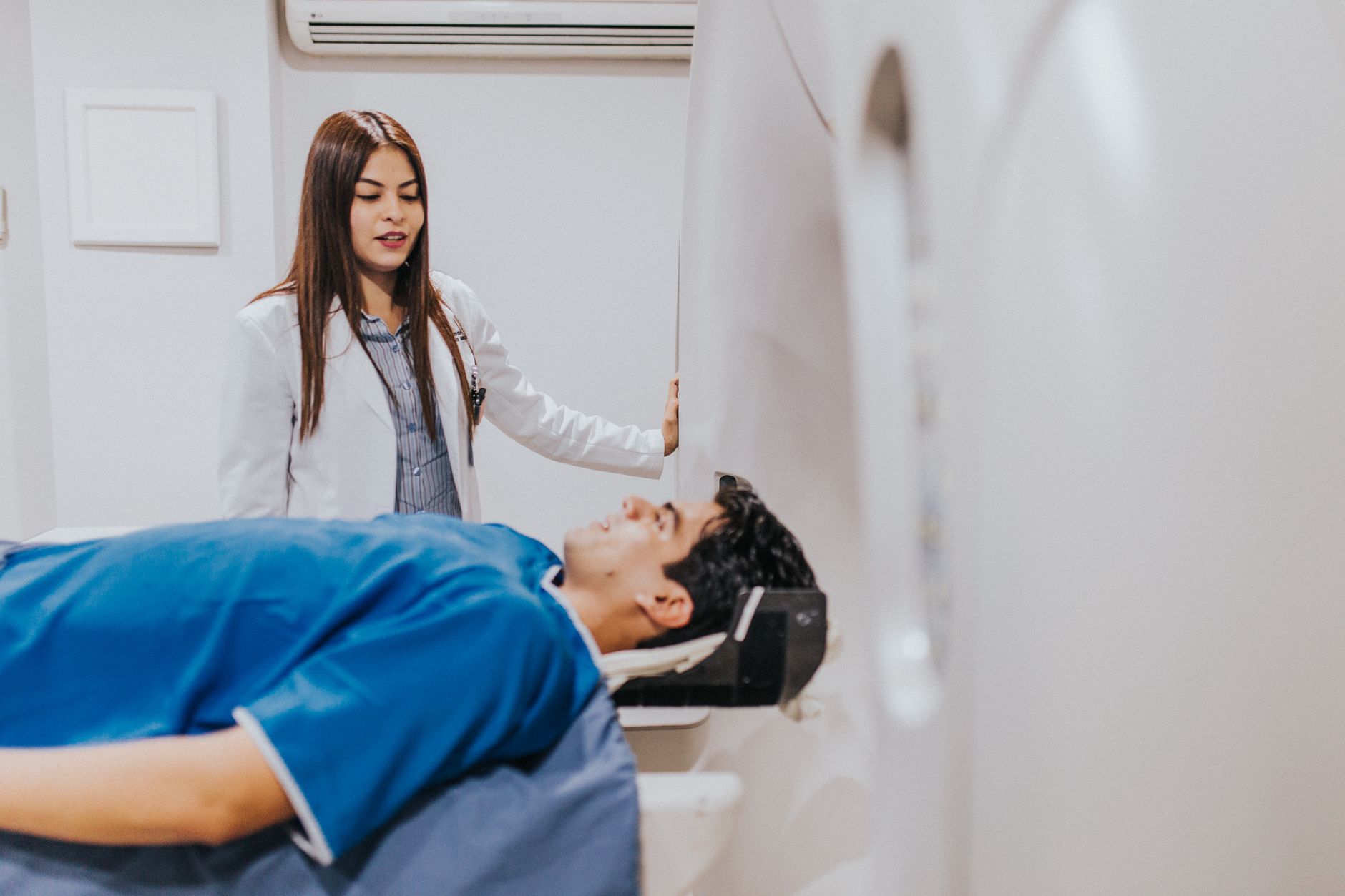 Doctor standing beside a patient in an MRI scanning room during a bone density screening