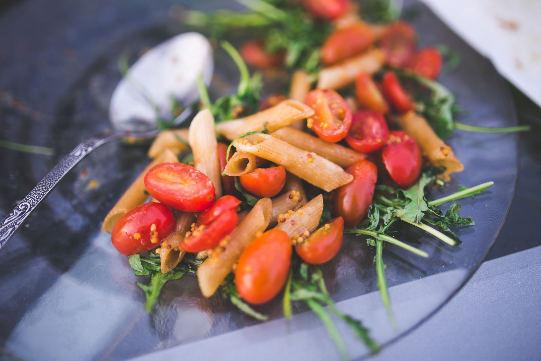 Fresh pasta salad with cherry tomatoes and arugula on a plate