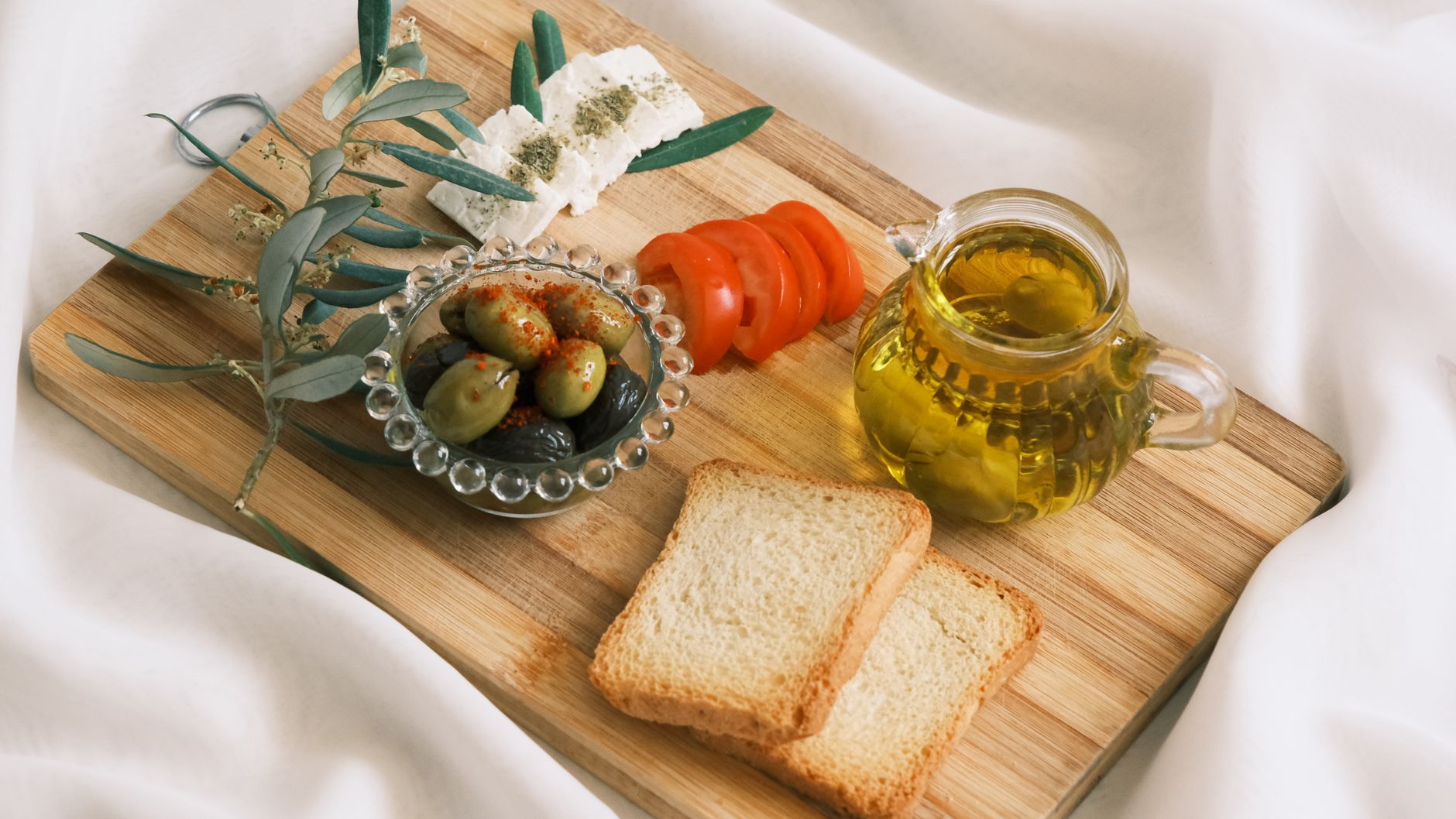 Rustic Mediterranean appetizer with olives, feta cheese, and olive oil on a wooden board