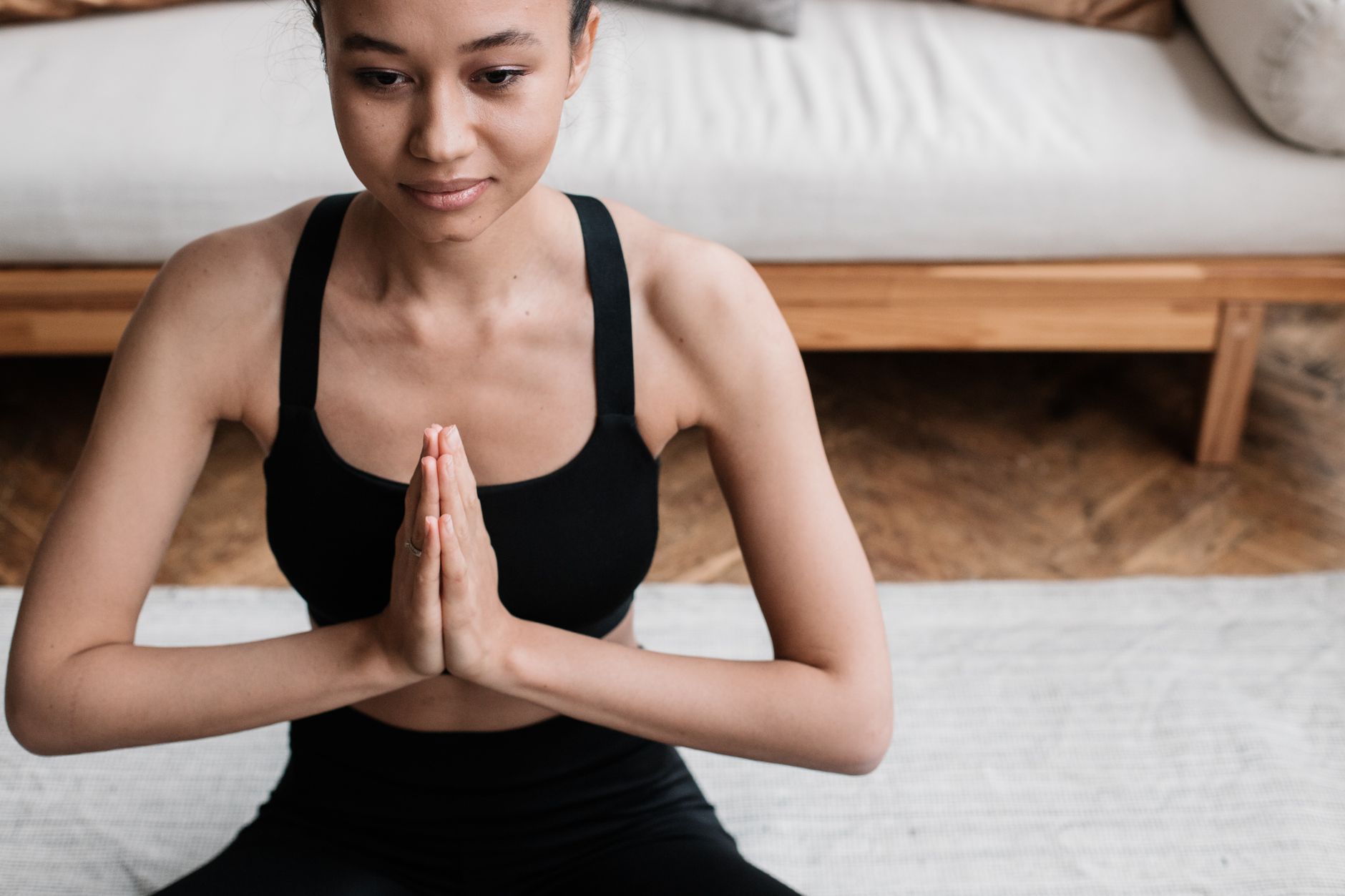 Woman in activewear meditating indoors representing stress relief and heart health