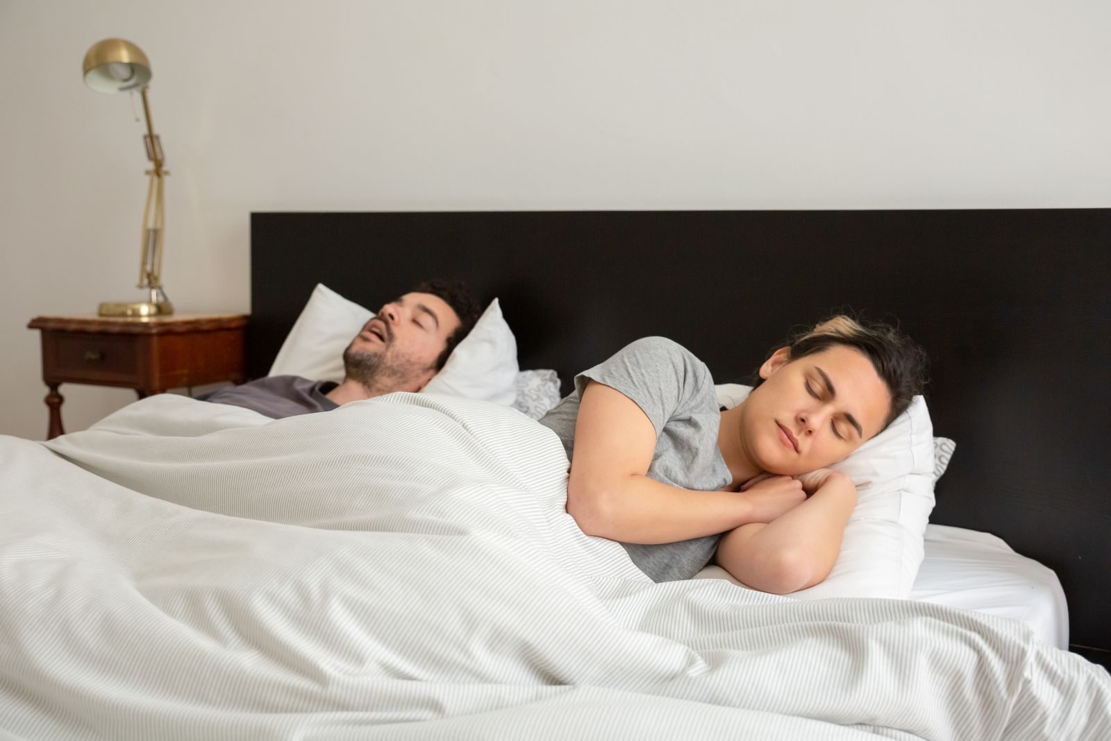 A couple soundly asleep in a cozy bedroom with classic decor, showcasing everyday serenity.